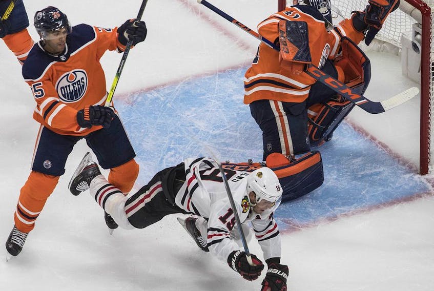 Edmonton Oilers' Darnell Nurse checks Chicago Blackhawks' Jonathan Toews as goalie Mike Smith makes the save during first period NHL playoff action in Edmonton, Aug. 1, 2020.
