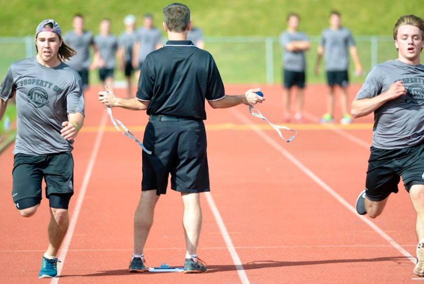 Kevin Elliott, centre, athletic therapist for the Charlottetown Islanders, times Brett Doiron, left, and Nathan Yetman as they sprint on the track at UPEI on Monday.&nbsp; <br /><br />