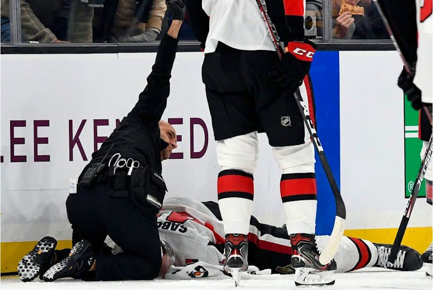A medical staff member calls for assistance while attending to Senators winger Scott Sabourin on the ice in Boston on Saturday evening.