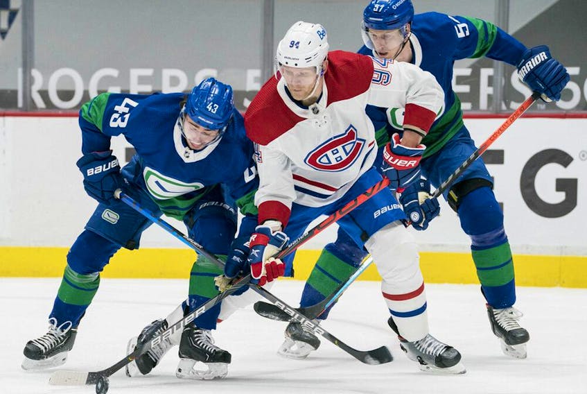 Canucks' Quinn Hughes (43) and Tyler Myers (57) check Canadiens' Corey Perry (94) in the third period at Rogers Arena in Vancouver on Saturday, Jan. 23, 2021. 