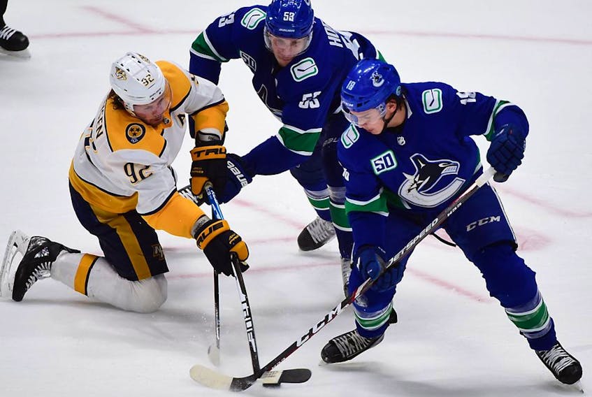 Nov 12, 2019; Vancouver, British Columbia, CAN; Nashville Predators forward Ryan Johansen (92) reaches for the puck against Vancouver Canucks forward Bo Horvat (53) and forward Jake Virtanen (18) during the third period at Rogers Arena. Mandatory Credit: Anne-Marie Sorvin-USA TODAY Sports