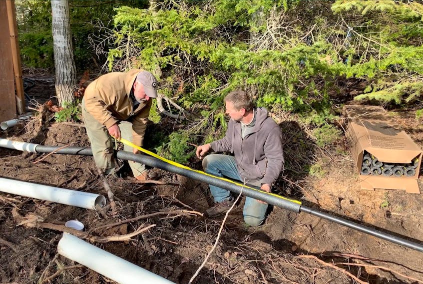 Steve and homeowner Brad installing an insulated and heated water line on a site with too little soil for frost protection. Brad says the fully encased, 150-foot-long installation has no noticeable effect on his electricity bill.