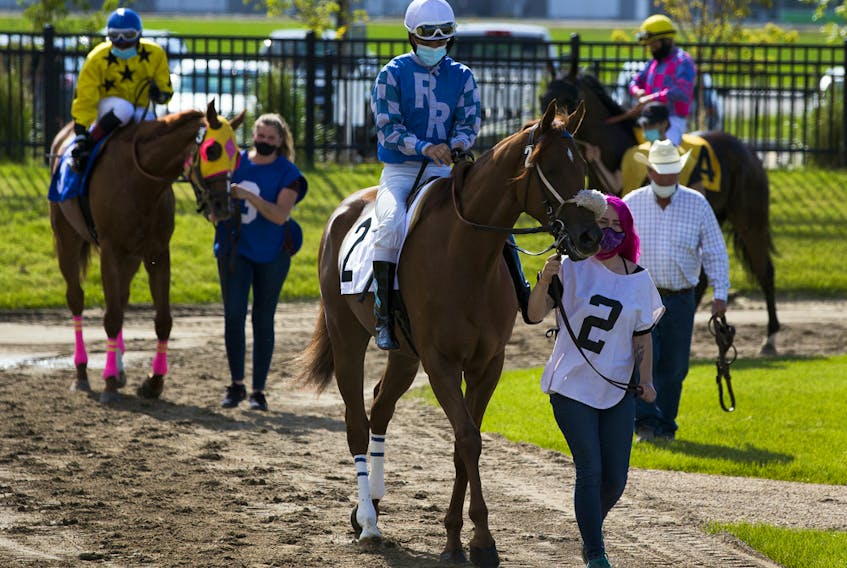 Jockeys prepare to leave the paddock on opening day of the season for Century Mile Racetrack on Sunday, June 21, 2020. No fans were allowed in the stands, just jockeys, horses and trainers.