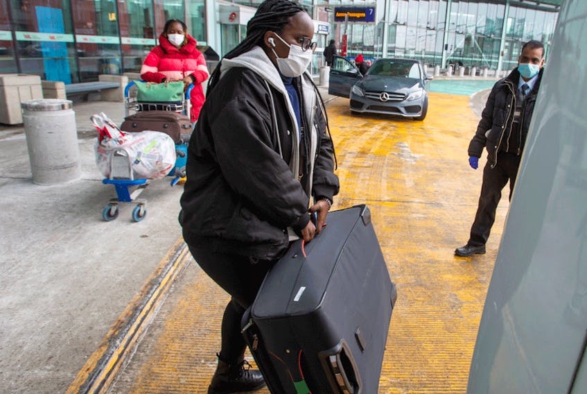 International air travellers load their luggage onto a shuttle bus to take them to one of the quarantine hotels Monday, February 22, 2021 in Montreal.