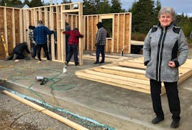 Barbara Lahey stands inside what will be her new home as a group of volunteers work behind her constructing it. Thanks to the kindness of the community, the 69-year-old widower is being given the home. NICOLE SULLIVAN/CAPE BRETON POST 