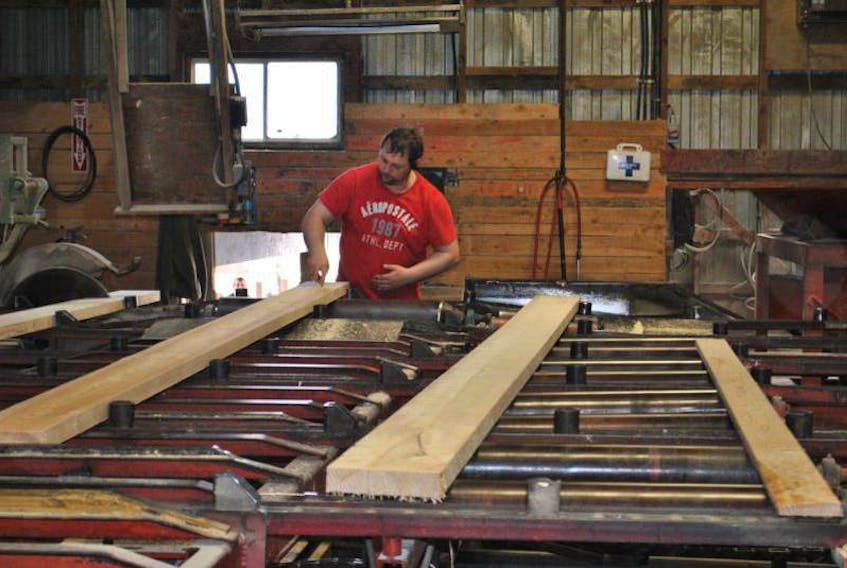 A worker at Williams Brothers Ltd. in Barneys River marks the length on a board produced at the sawmill in this file photo. 