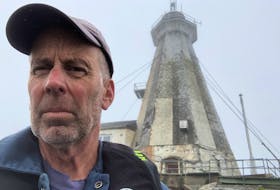 Chris Mills poses with the  Gannet Rock Lighthouse in the background, Chris had been the lighthouse keeper for two and a half years.