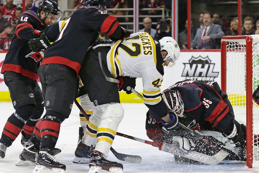 Boston Bruins' David Backes (42) tries to score against Carolina Hurricanes goalie Curtis McElhinney (35) while Hurricanes' Calvin de Haan (44) and Justin Faulk defend during the first period in Game 3 of the NHL hockey Stanley Cup Eastern Conference final series in Raleigh, N.C., Tuesday, May 14, 2019. (AP Photo/Gerry Broome) 