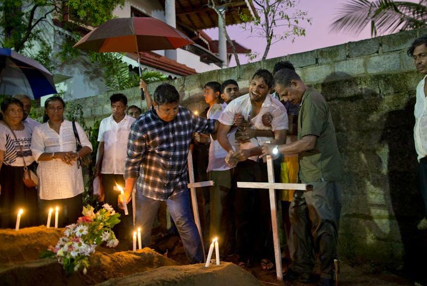 Relatives place flowers after the April 22, 2019 burial of three victims of the same family, who died in an Easter Sunday bomb blast at St. Sebastian Church in Negombo, Sri Lanka.  (AP Photo/Gemunu Amarasinghe) 