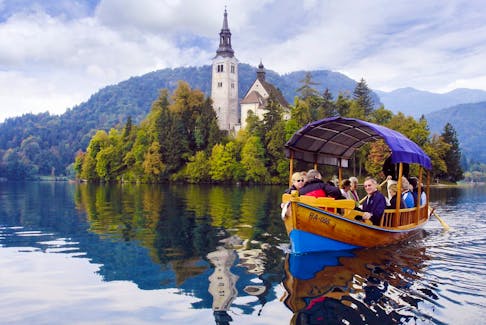 Visitors enjoy a scenic ride to a Lake Bled island on a traditional pletna boat. (Cameron Hewitt)