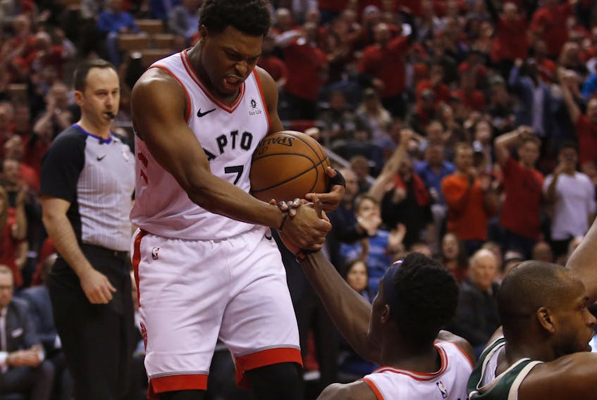 Toronto Raptors' Kyle Lowry helps teammate Pascal Siakim up during Tuesday's game. (JACK BOLAND/Toronto Sun)