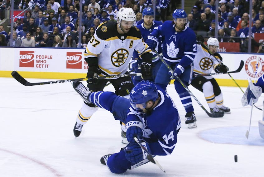 Defenceman Morgan Rielly, who played one of his finest games in a Leafs uniform on Sunday, hits the ice after blocking shot while Bruins Patrice Bergeron looks on. — Veronica Henri/Toronto Sun/Postmedia Network)