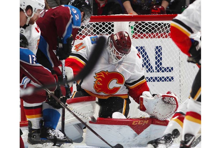 CP-Web.  Colorado Avalanche goaltender Pavel Francouz, left, looks to stop a shot off the stick of Calgary Flames center Dillon Dube, front right, as he jostles in front of the net with Colorado defenseman Ryan Graves in the second period of an NHL hockey game Monday, Dec. 9, 2019, in Denver.