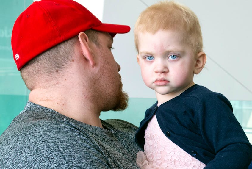 Two-year-old Lyana Deslauriers is held by her father Joel.