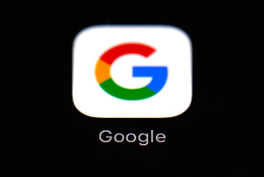 A woman takes a picture with two smartphones in front of the logo of the U.S. multinational technology and Internet-related services company Google.  (ALAIN JOCARD/Getty Images)