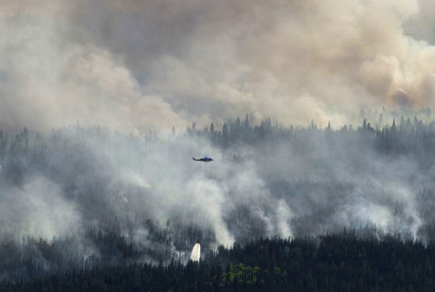 A helicopter drops a bucket of water on the Chuckegg Creek wildfire west of High Level, Alta., in a Saturday, May 25, 2019, handout photo.