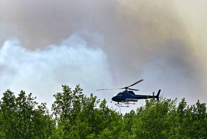 A helicopter flys tree-top level ahead of wildfire crews doing controlled burn ignition operation approximately three kilometres southwest of High Level where about 5,000 residence were evacuated from the Chuckegg Creek fire, May 23, 2019. Ed Kaiser/Postmedia