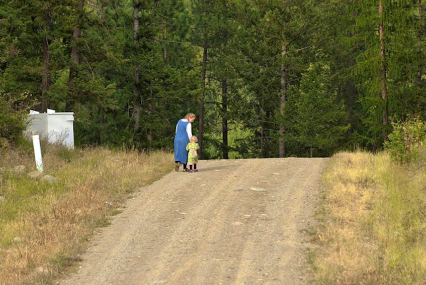  A woman and child walk down the road in the Bountiful community near Creston, B.C.