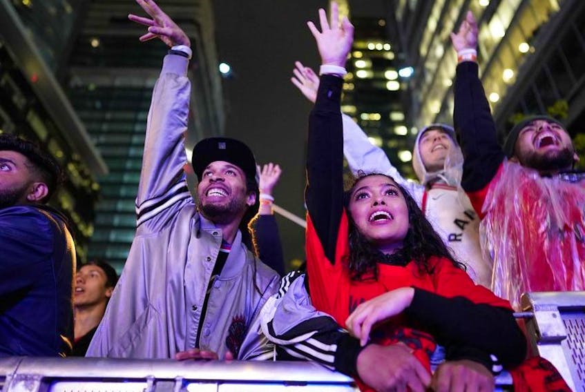 In this file photo taken on June 10, 2019 Toronto Raptor fans cheer during a street party in Jurassic Park, outside of Scotiabank Arena in Toronto, Ontario, during Game 5 of the NBA Championships against the Golden State Warriors. -