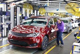 In this Dec. 7, 2018, file photo, inspector Frank Calzavara is shown with a Chrysler Pacifica Hybrid in velvet red in the Final Car area of FCA Windsor Assembly Plant.