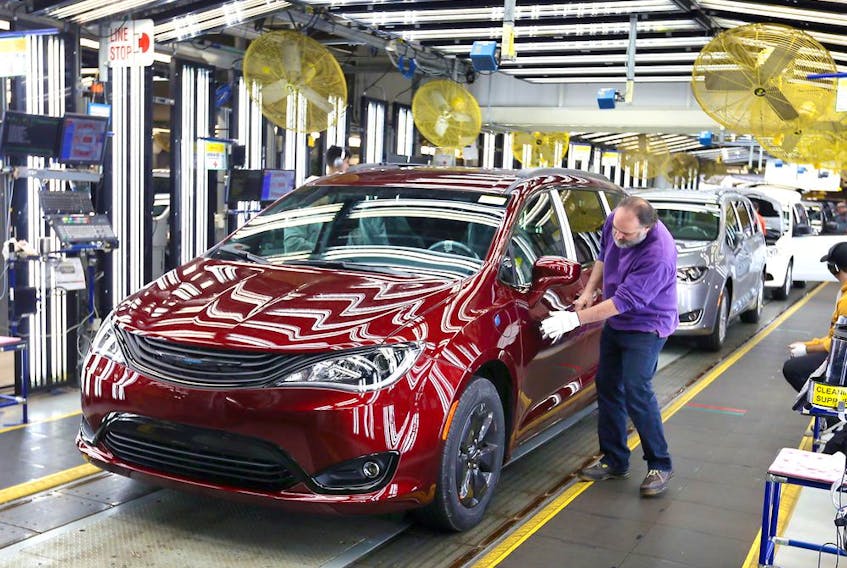 In this Dec. 7, 2018, file photo, inspector Frank Calzavara is shown with a Chrysler Pacifica Hybrid in velvet red in the Final Car area of FCA Windsor Assembly Plant.
