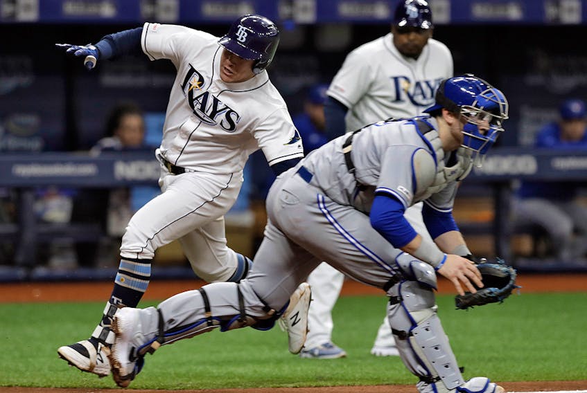 Tampa Bay Rays' Avisail Garcia, left, scores around Toronto Blue Jays catcher Danny Jansen on an inside-the-park home run during the third inning of a baseball game, Tuesday, May 28, 2019, in St. Petersburg, Fla.