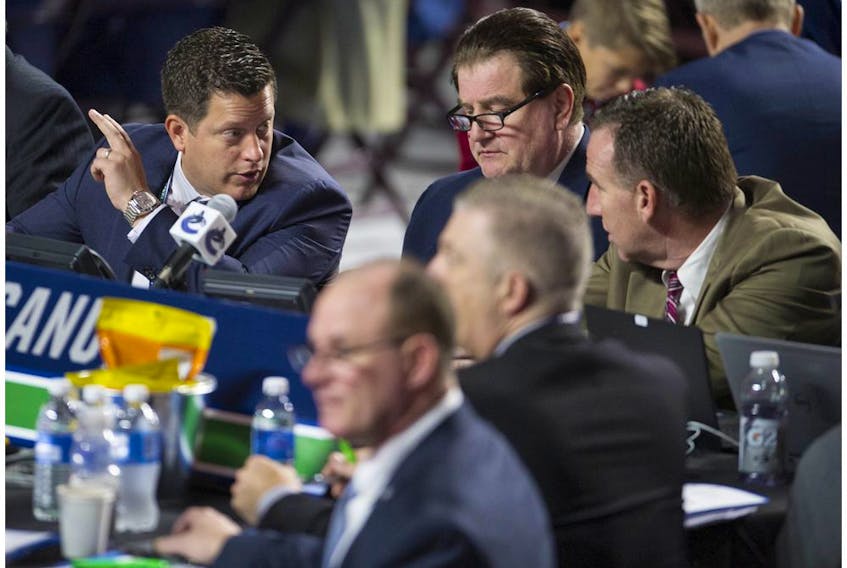  Scouting director Judd Brackett, left, talks to Vancouver Canucks’ GM Jim Benning, centre, and AGM John Weisbrod during the 2019 NHL Entry Draft at Rogers Arena in Vancouver. Brackett wanted some conditions before accepting a two-year contract extension from the NHL club, but Benning refused to budge.