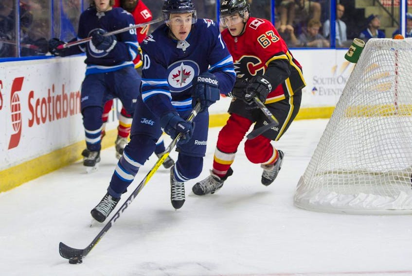 Winnipeg Jets Leon Gawanke (left) picks up the puck from behind his net while pressured by Calgary Flames Adam Ruzicka during NHL preseason hockey action at the Young Stars Classic held at the South Okanagan Events Centre in Penticton, BC, September, 11, 2017. On Thursday, the Jets announced they've signed Gawanke to an entry level contract. (Richard Lam/PNG