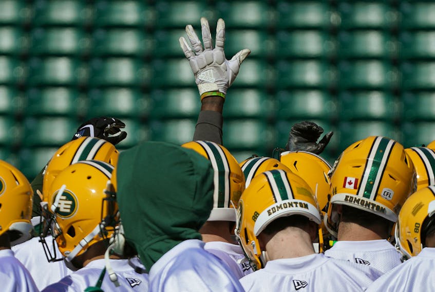 A lone hand is raised during a team huddle at the Edmonton Eskimos training camp held at Commonwealth Stadium on May 20, 2019. The CFL has announced the postponement of 2020 training camps amid COVID-19 measures.
