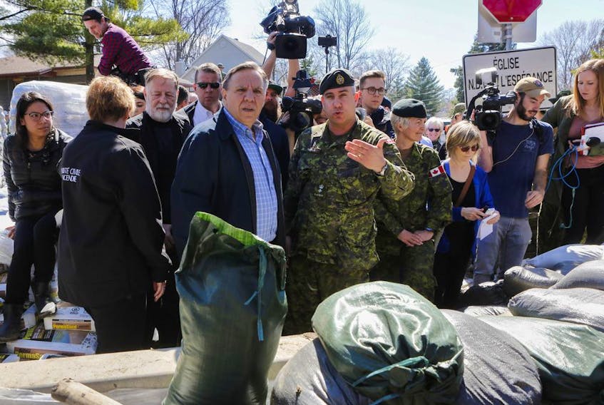 Premier François Legault looks towards the encroaching Rivière des Prairies beside a wall of sand constructed by Canadian military in the Ile Bigras area of Laval near Montreal Sunday, April 21, 2019. 
