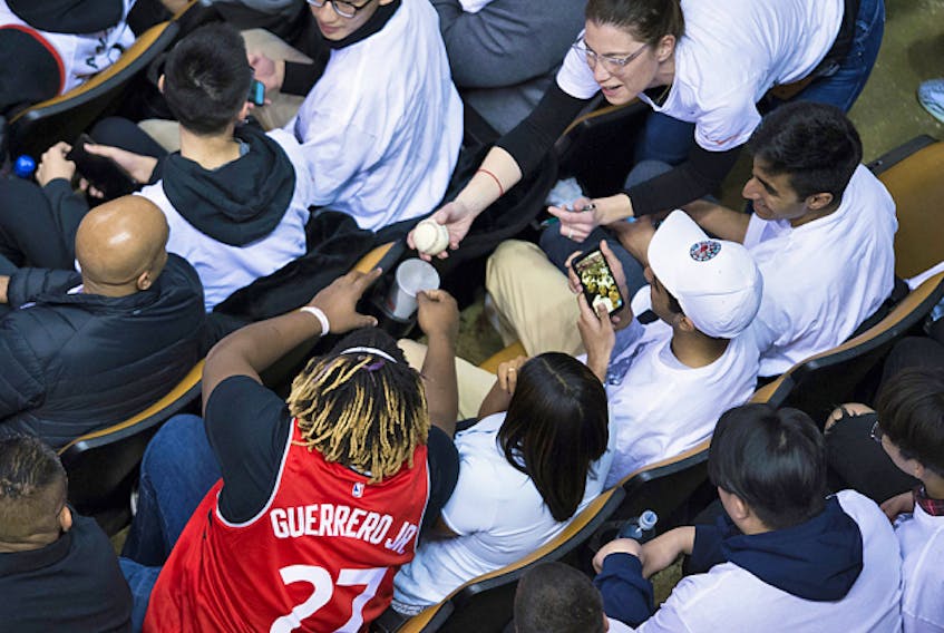  Toronto Blue Jays third baseman Vladimir Guerrero Jr. (27) signs a baseball for a fan during the action between the Toronto Raptors and the Philadelphia 76ers, in Toronto on Saturday, April 27, 2019.
