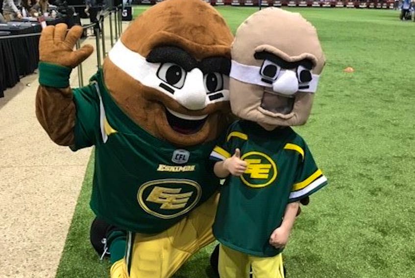 Young fan Hudson Groening, right, poses with the Edmonton Eskimos mascot Punter. 