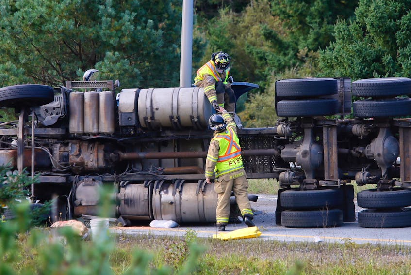 Halifax firefighters examine a tractor-trailer that flipped onto its side Monday, Oct. 1, 2018 on Highway 118 at Fall River. (Tim Krochak / The Chronicle Herald)