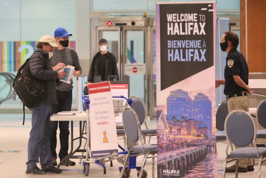 Air passengers who just arrived on a flight from St. John's speak to a member of Nova Scotia heath enforcement staff in the baggage area of Halifax Stanfield International Airport on Thursday, July 2, 2020.