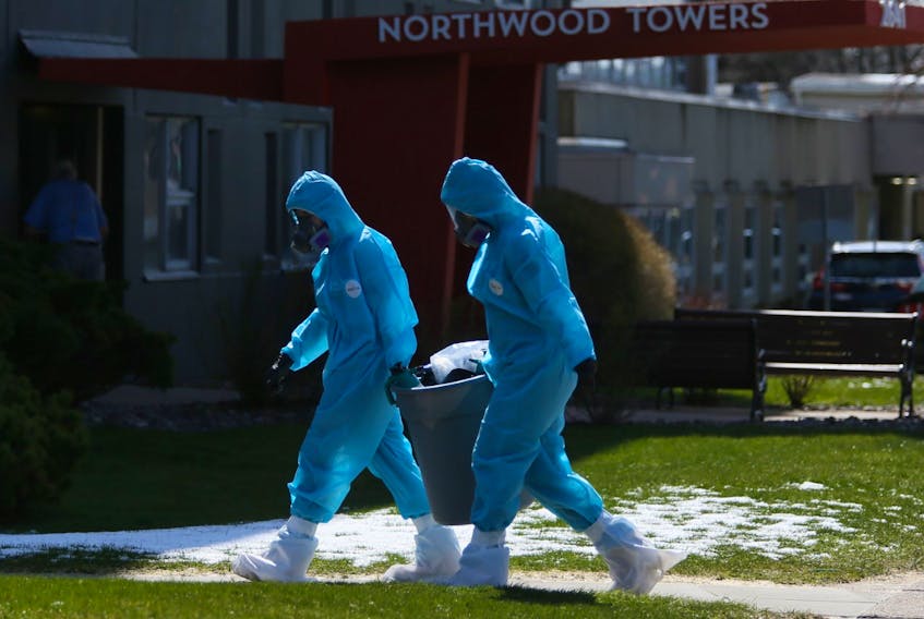 Workers in full personal protective equipment remove a trash can from Northwood Towers in Halifax on Wednesday, April 29, 2020. Northwood has had the most COVID-19 related deaths in the province, 21 out of 27 deaths that have occurred up until today.