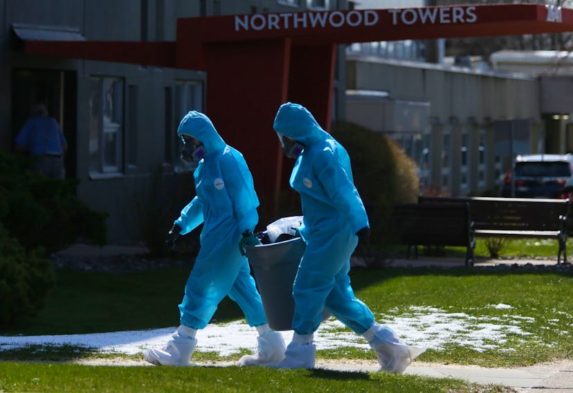 Workers in full personal protective equipment remove a trash can from Northwood Towers in Halifax on Wednesday, April 29, 2020. Northwood has had the most COVID-19 related deaths in the province, 21 out of 27 deaths that have occurred up until today.