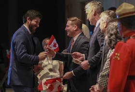 Tareq Hadhad, CEO and founder of Peace by Chocolate,  gets a flag from federal Immigration Minister Marco E.L. Mendicino as he becomes a Canadian citizen in Halifax on Wednesday, Jan. 15, 2020. Hadhad was one of  50 new citizens sworn in at a special citizenship ceremony held at the Canadian Museum of Immigration at Pier 21.