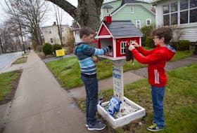 Rylan, 13, and Bren DeCoste, 8, put non-perishables and face masks into the School House pantry on the front lawn of their Dartmouth home Monday, May 4, 2020. Their mother Jennifer said that the food is going out quickly these days.