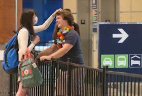 Chloe Puddister plays with the hair of her boyfriend, Hayden Goss, as the couple reunites in the baggage area of Halifax Stanfield International Airport on Thursday, July 2, 2020 after spending the last three-and-a-half months apart. Chloe had just arrived from a flight from St. John's.
