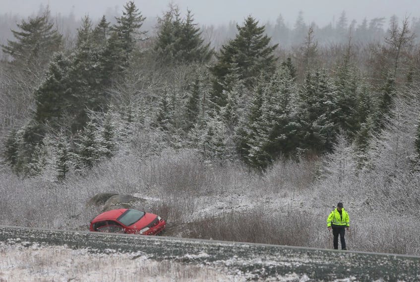 A police officer stands near the site of a fatal crash on Highway 103 near the Lakeside exit, on Wednesday, Dec. 11, 2019.