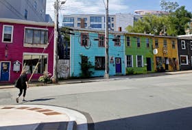 A woman walks past colourful rowhouses on Queen Street in Halifax on Wednesday, Sept. 9, 2020. The buildings are slated to be knocked down to make way for a new development.