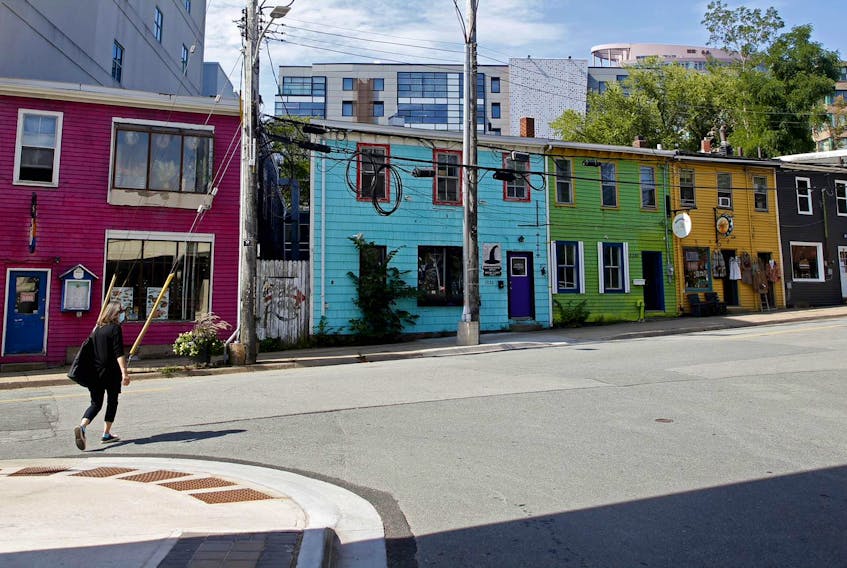 A woman walks past colourful rowhouses on Queen Street in Halifax on Wednesday, Sept. 9, 2020. The buildings are slated to be knocked down to make way for a new development.