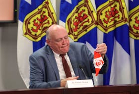 Dr. Robert Strang, Nova Scotia's chief medical officer of health, removes his non-medical mask before the start of a news briefing in Halifax on Friday, Aug. 14, 2020.