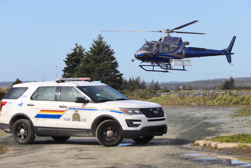 A helicopter takes off behind an RCMP vehicle at Rainbow Have Beach provincial park near Cole Harbour on Thursday, Oct. 1, 2020.