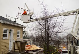 A Nova Scotia Power employee works on cutting down some staging that got stuck on a roof and power lines of a home on Marvin Avenue in Dartmouth on Tuesday, Dec. 10, 2019. A house under construction next to it collapsed due to high winds.
