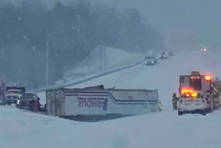 Emergency responders work near a tractor trailer that rolled over into the median on Highway 101 near St. Croix during the last official storm of the winter Friday morning, March 19, 2021.