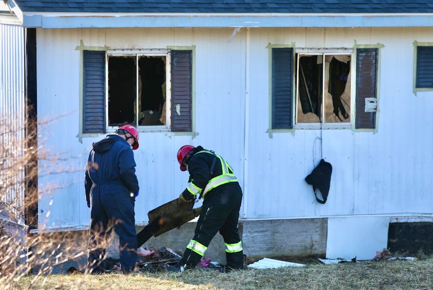 Fire investigators look through debris outside a home at 31 Spruce Dr. in Eastern Passage on Tuesday, Jan. 19, 2021.