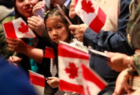 A youngster looks out from among miniature Canadian flags during a citizenship ceremony in Halifax on Wednesday, Jan. 15, 2020. Fifty new citizens were sworn in at a special citizenship ceremony at the Canadian Museum of Immigration at Pier 21.