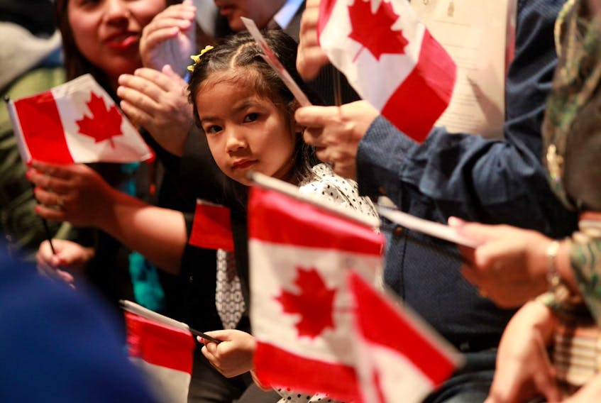 A youngster looks out from among miniature Canadian flags during a citizenship ceremony in Halifax on Wednesday, Jan. 15, 2020. Fifty new citizens were sworn in at a special citizenship ceremony at the Canadian Museum of Immigration at Pier 21.