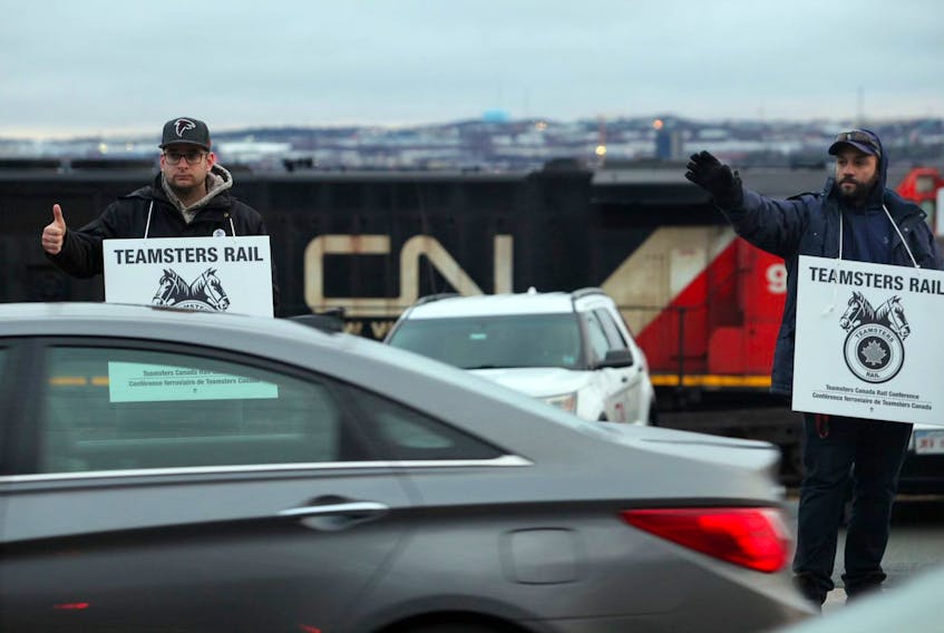 Striking CN Rail workers wave in response to honks from motorists along the Bedford Highway in Halifax on Tuesday morning, Nov, 19, 2019.